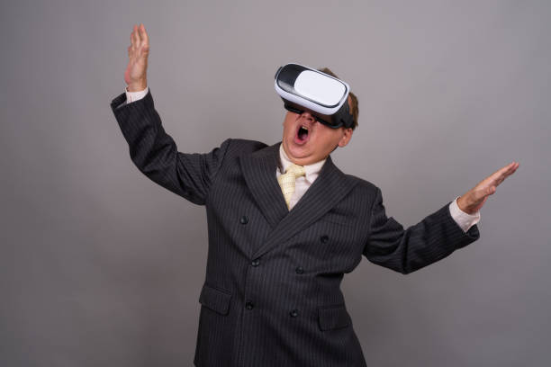 istock Studio shot of mature Asian businessman using Virtual Reality headset against gray background 818566366