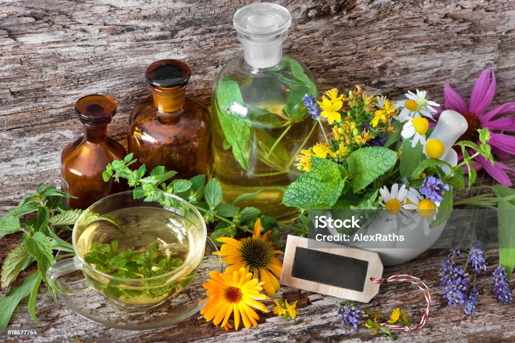 Cup of herbal tea with medicinal bottles and healing herbs in mortar Cup of herbal tea with tincture bottles and healing herbs in mortar on wooden table. Herbal medicine. Medicinal plants Absinthe Stock Photo