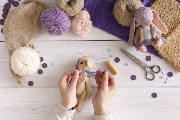 Process of making vintage toy, top view. Artisan pov, needlewoman hands sewing handmade teddy bear, home workshop