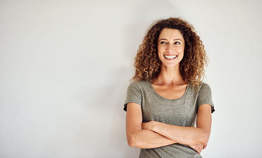 Shot of a happy and confident young woman standing posing against a gray wall
