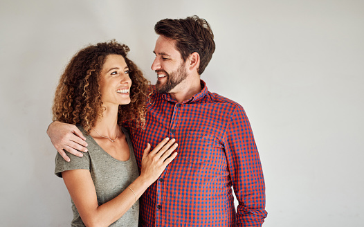 Shot of a happy and loving young couple standing together against a gray wall