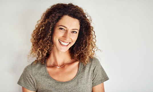 Portrait of a happy and confident young woman standing posing against a gray wall