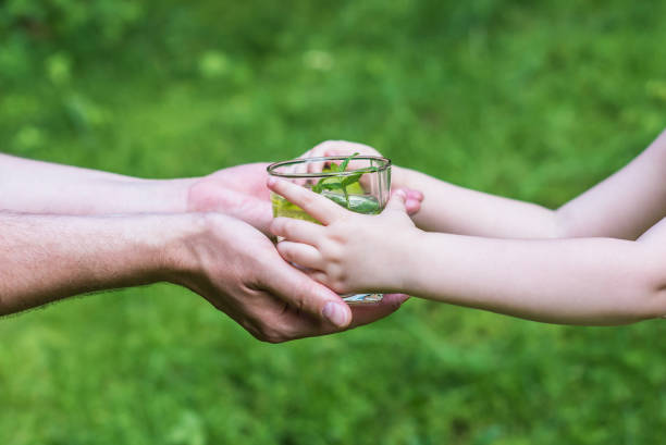 istock Man giving water to child 818644460
