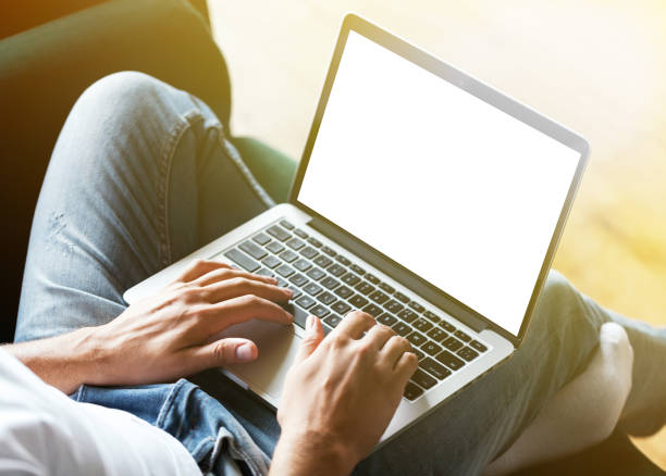 istock Man's hands using laptop with blank screen on desk in home interior. Work concept 818646962