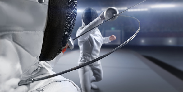 Two fencers dueling in a fencing sports match. Foil swords clashing to determine the match winner