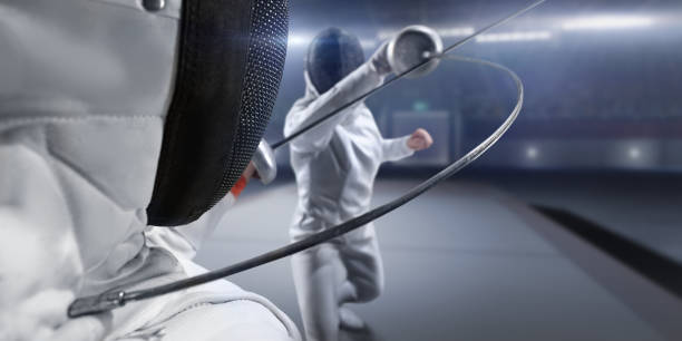 Female fencer fight on big professional stage Fencing competitive duel. Female fencer fight on big professional stage. They are wearing an unbranded fencing suit. face guard sport stock pictures, royalty-free photos & images