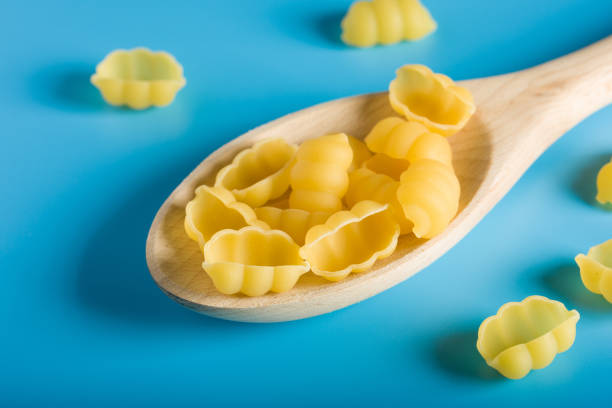 istock Raw Pasta on Wood Spoon in blue background 818652238