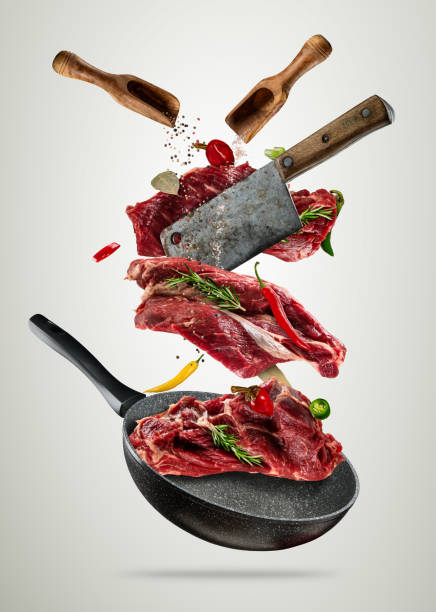 istock Flying raw steaks with cooking ingredients from pan 818653530