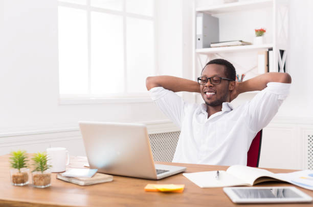 istock Relaxed black businessman with laptop in modern white office 818668118