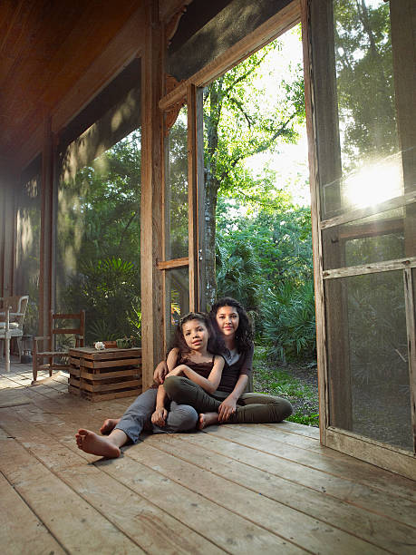 two mixed race young girls embrace each other sitting on screened porch - full length florida tropical climate residential structure zdjęcia i obrazy z banku zdjęć