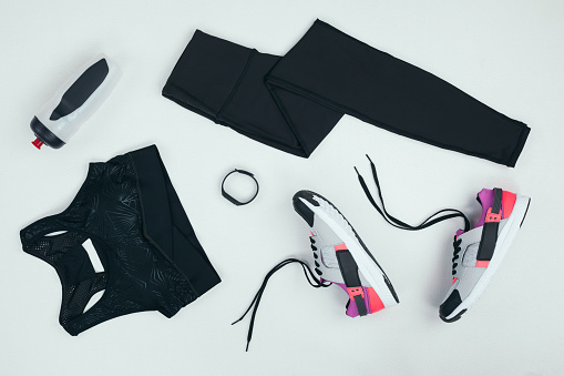 lay Flat con ropa deportiva con zapatillas de deporte, rastreador de fitness y deportes botella aislada en gris photo