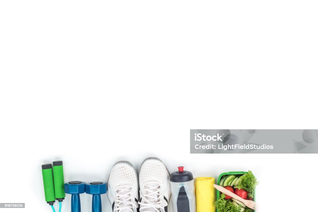 top view of dumbbells, skipping rope, sports shoes, bottle of water and vegetable salad isolated on white White Background Stock Photo