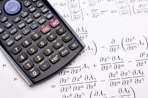 Close up shot of scientific calculator and mathematical equations sheets