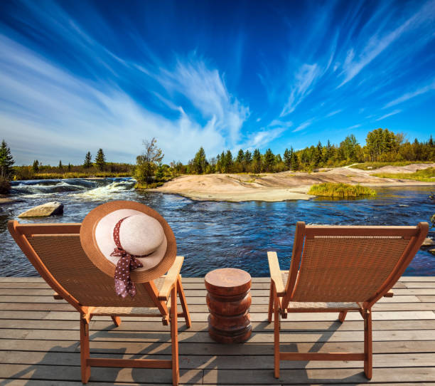 Lovely place to relax. Two beach chairs and hat on the riverbank. Winnipeg River, Old Pinawa Dam Park. The concept of recreational tourism