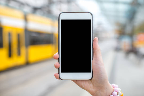 istock Holding a smart phone on the tram stop background 818772578