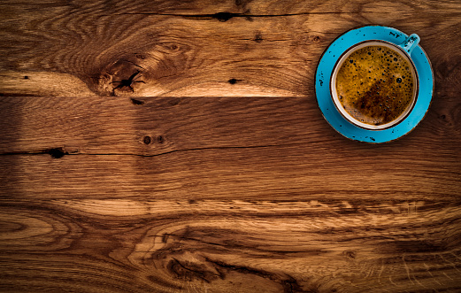 Cup of coffee on dark brown wooden table, above view