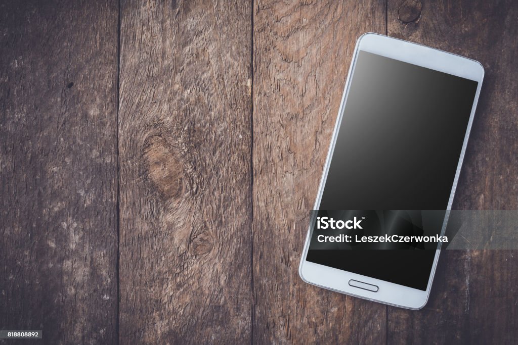 Modern white smart phone on wooden table. Modern white smart phone on wooden table. Close up Telephone Stock Photo