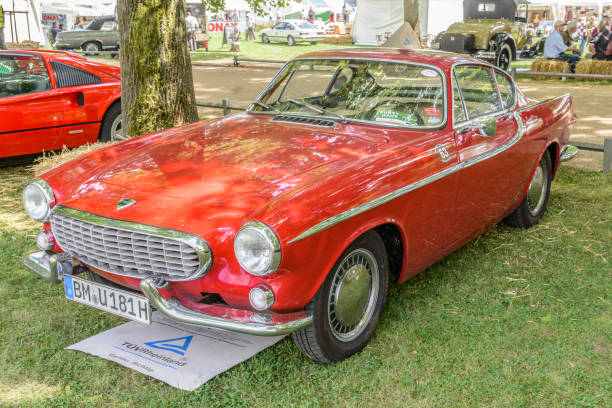 Volvo P1800S classic Swedish coupe car on display at the 2016 Classic Days at Dyck Castle in Jüchen, Germany. People in the background are looking at the cars.