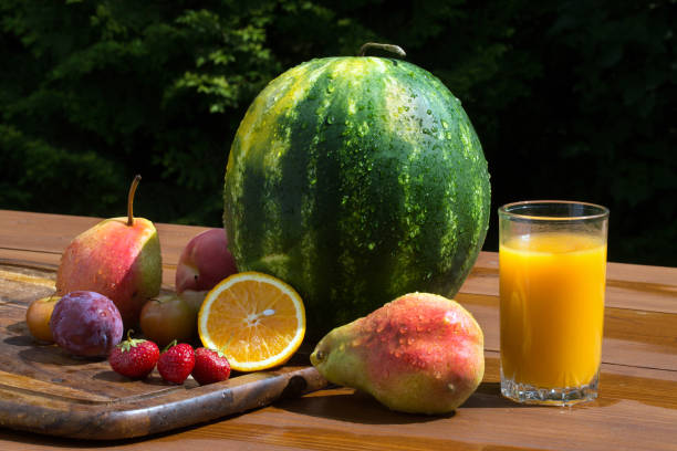 istock Fruit and orange juice on a table in the garden 818828106
