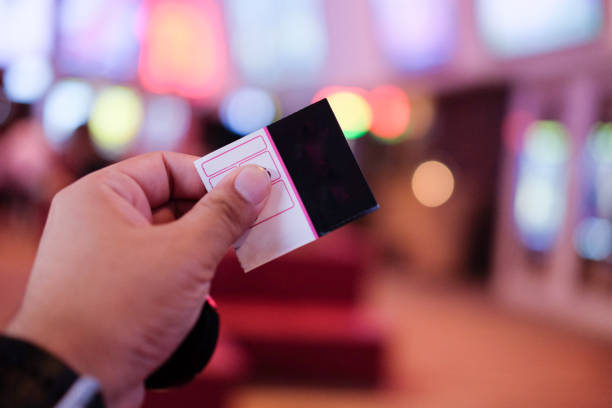 istock Young man's hand holding a paper ticket on blurred cinema complex background 818831768