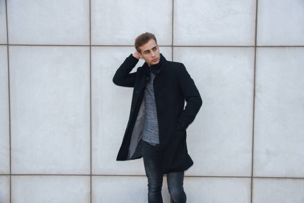 istock Young handsome modern blond businessman leaning against a white wall. 818848778