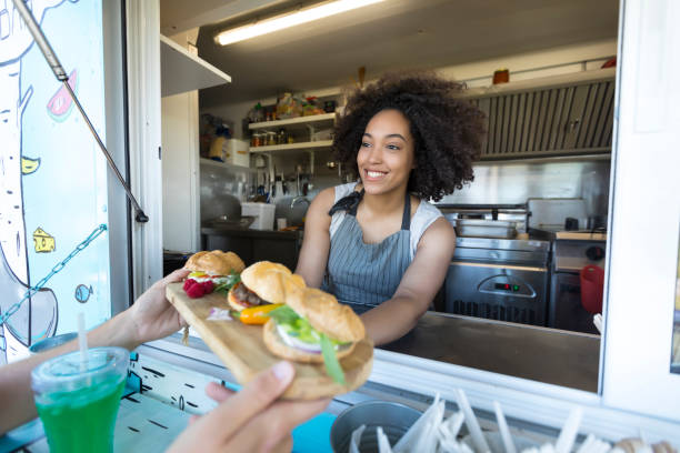 istock Smiling food van worker offering sandwiches 818872792