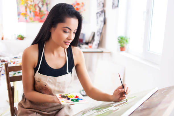 artista femminile sorridente che disegna in studio - easel artists canvas paint paintings foto e immagini stock