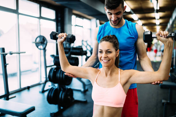 istock Beautiful woman doing exercises in gym with personal trainer 818880384