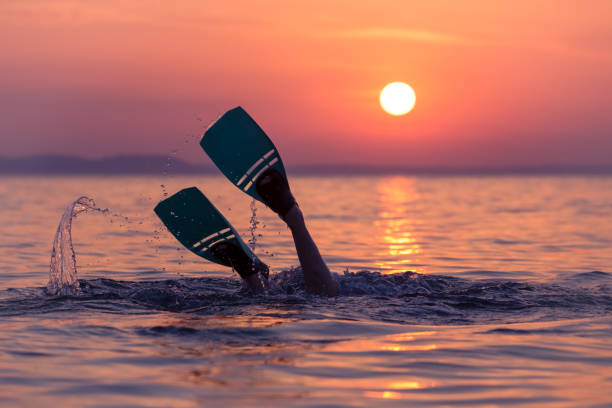 Close up of scuba diver feet with snorkel fins start diving at sunset