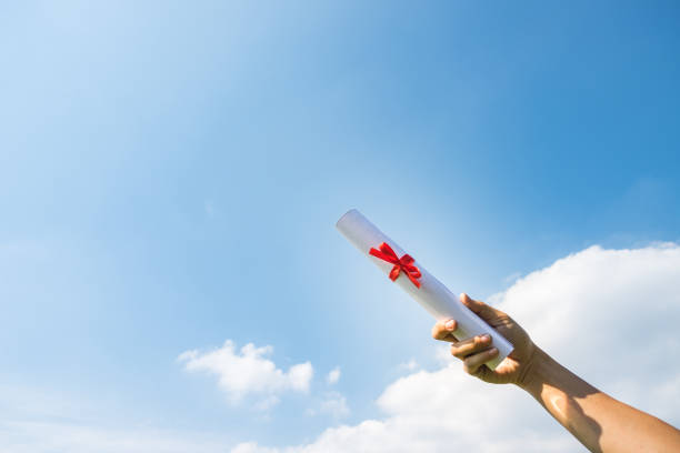 istock Hand holding Graduation certificate roll under the sunshine, blue sky background. 818890552