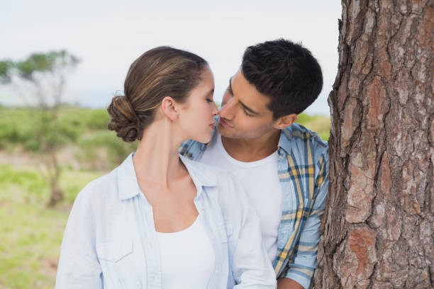 istock Romantic couple about to kiss by tree trunk 818894616