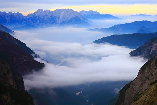 Above Idyllic mist covered Tre Cime di Lavaredo pinnacle and Auronzo di cadore lake, massif mountain range, clouds above Puster valley, dramatic sky at moody dawn, dramatic panorama and majestic Dolomites, Italy tirol alps