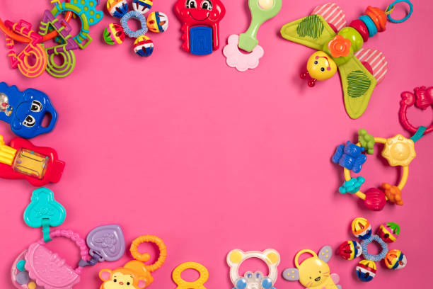 istock Children's rattle from plastic on a pink background. Top view 818929208