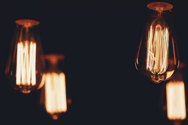 istock Close-up of glowing retro light bulbs on a black background. 818935618