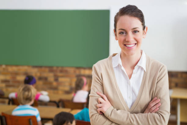 istock Pretty teacher smiling at camera at back of classroom 819093312
