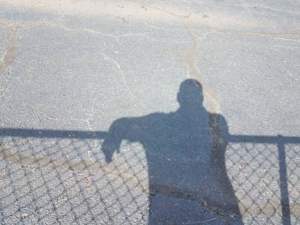 istock shadow of man with shadow of fence 819111444