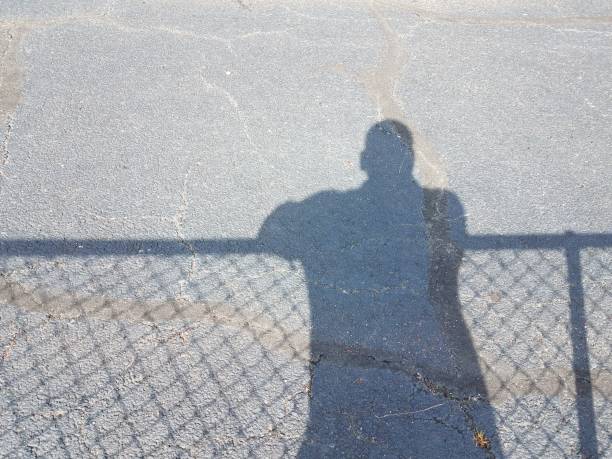 istock shadow of man with shadow of fence 819111682