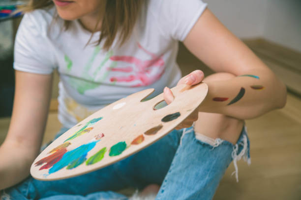 istock Happy young woman paints on canvas 819137704