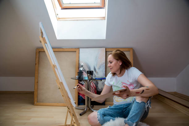 istock Happy young woman paints on canvas 819138092