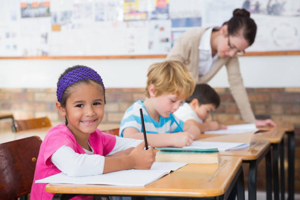 istock Cute pupils drawing at their desks one smiling at camera 819139580
