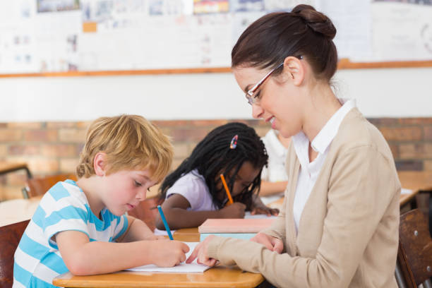 istock Pretty teacher helping pupil in classroom 819140092
