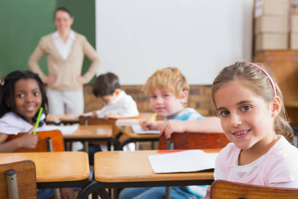 istock Pupils and teacher smiling at camera in classroom 819142634