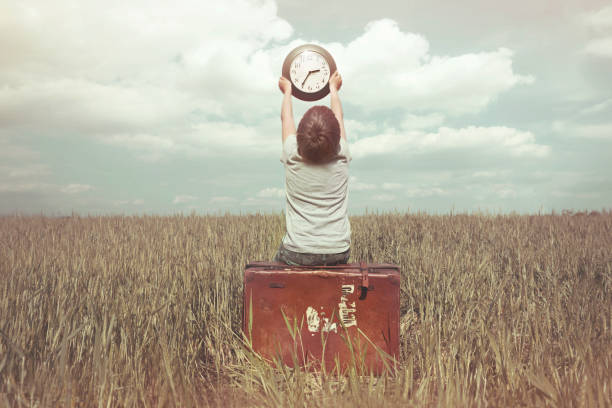 little boy raises in the sky a watch in a surreal landscape - abstract senior adult old past imagens e fotografias de stock