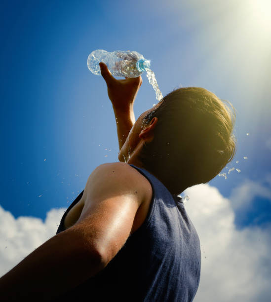 istock Young man splashing and pouring fresh water from a bottle on his head 819167028