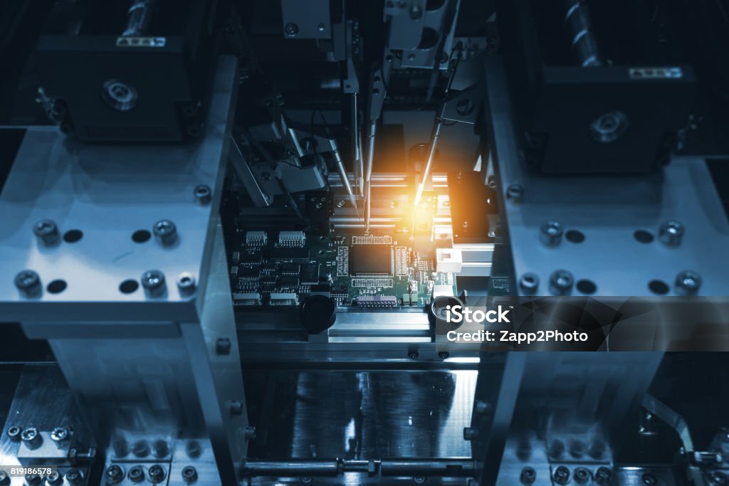 Selective focus to PCB circuit board. Automation of machine industry assembly of computer circuit board in smart factory for production computer components. Blue tone with flare light. Semiconductor Stock Photo