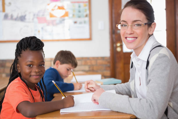 istock Cute pupil getting help from teacher in classroom 819186872