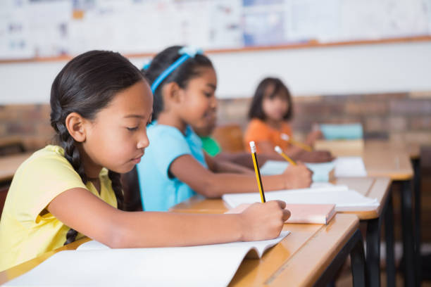 istock Cute pupils writing at desk in classroom 819186936