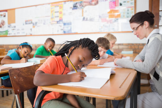 istock Cute pupils writing at desk in classroom 819187314