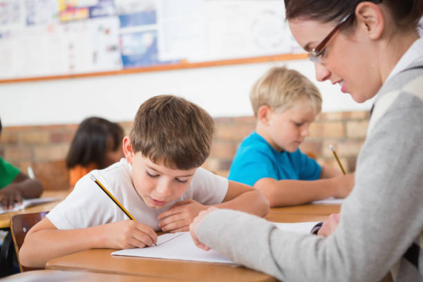 istock Cute pupils writing at desk in classroom 819187380