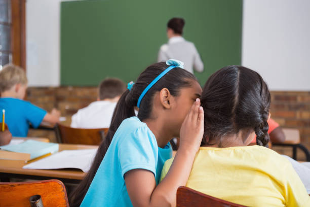 istock Cute pupils whispering in classroom 819188998